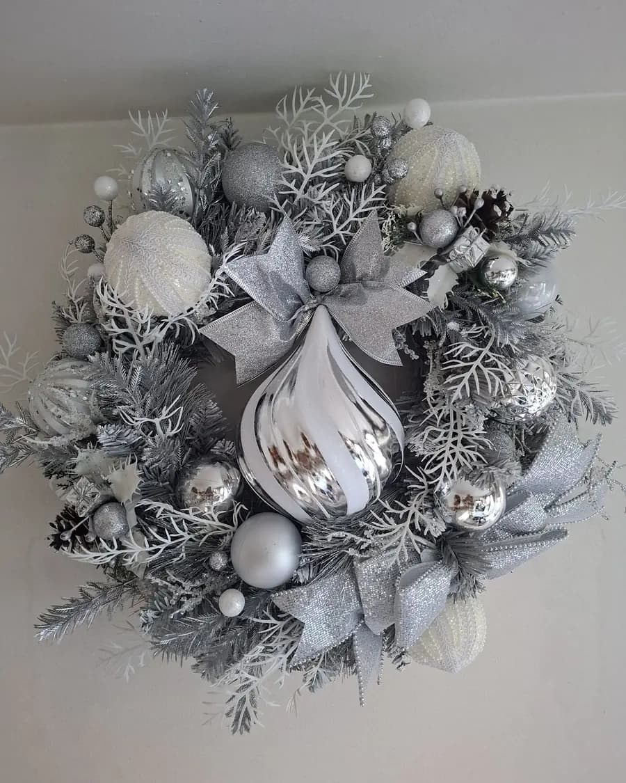 A silver and white Christmas wreath with a large teardrop bauble at its centre.