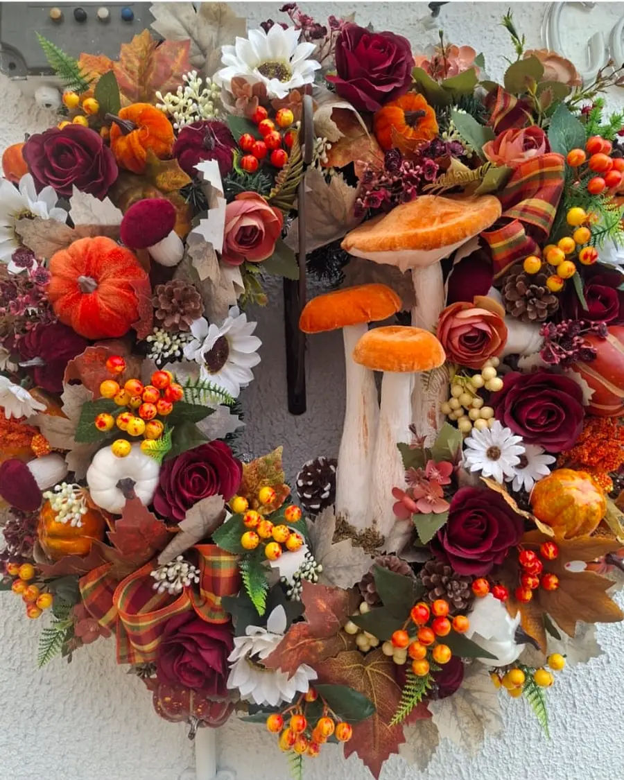 An autumn wreath of burgundy roses, orange pumpkins and three large fabric toadstools.