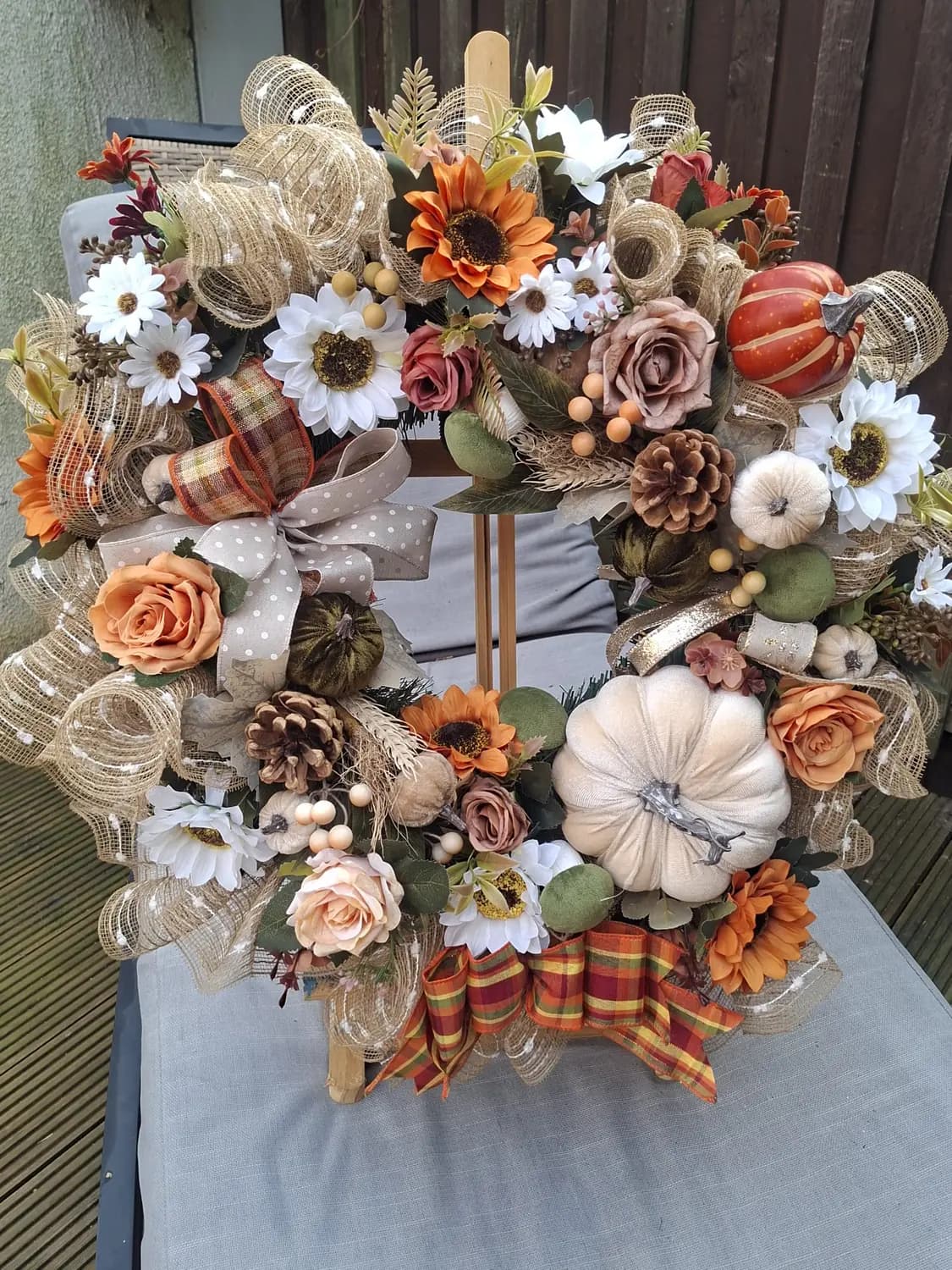 An autumn wreath with sunflowers, white and orange pumpkins, hessian and tartan ribbon.